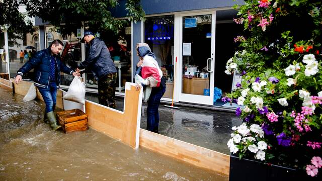 Ondernemers in het centrum van Valkenburg proberen hun winkel te beschermen tegen het water.