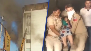 Hulpdiensten dragen vrouw uit brandend hotel in India