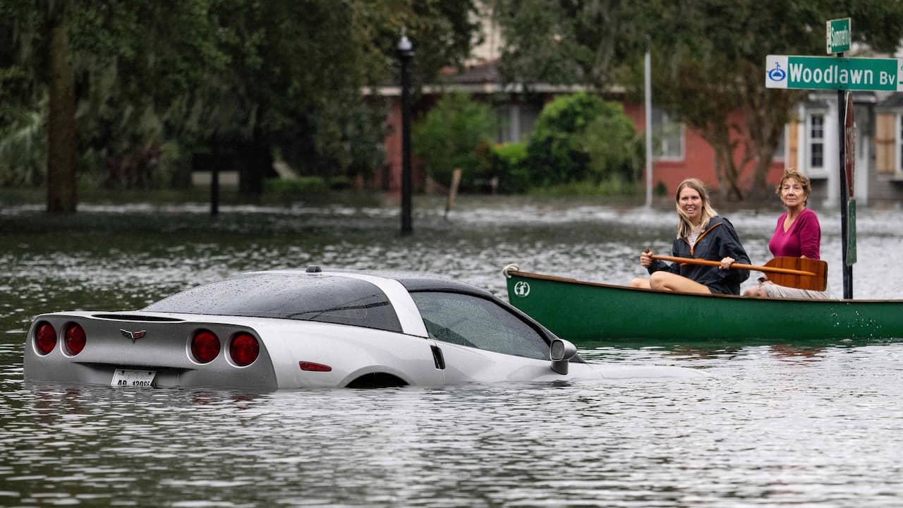 Due donne in canoa per le strade della Florida centrale di Orlando.  È l'unico modo per spostarsi in alcune parti della città, come mostra la Chevy Corvette semiaffondata.