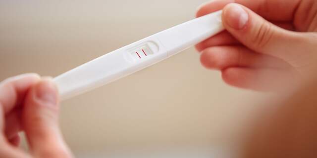 vrouw houdt zwangerschapstest vast in hand