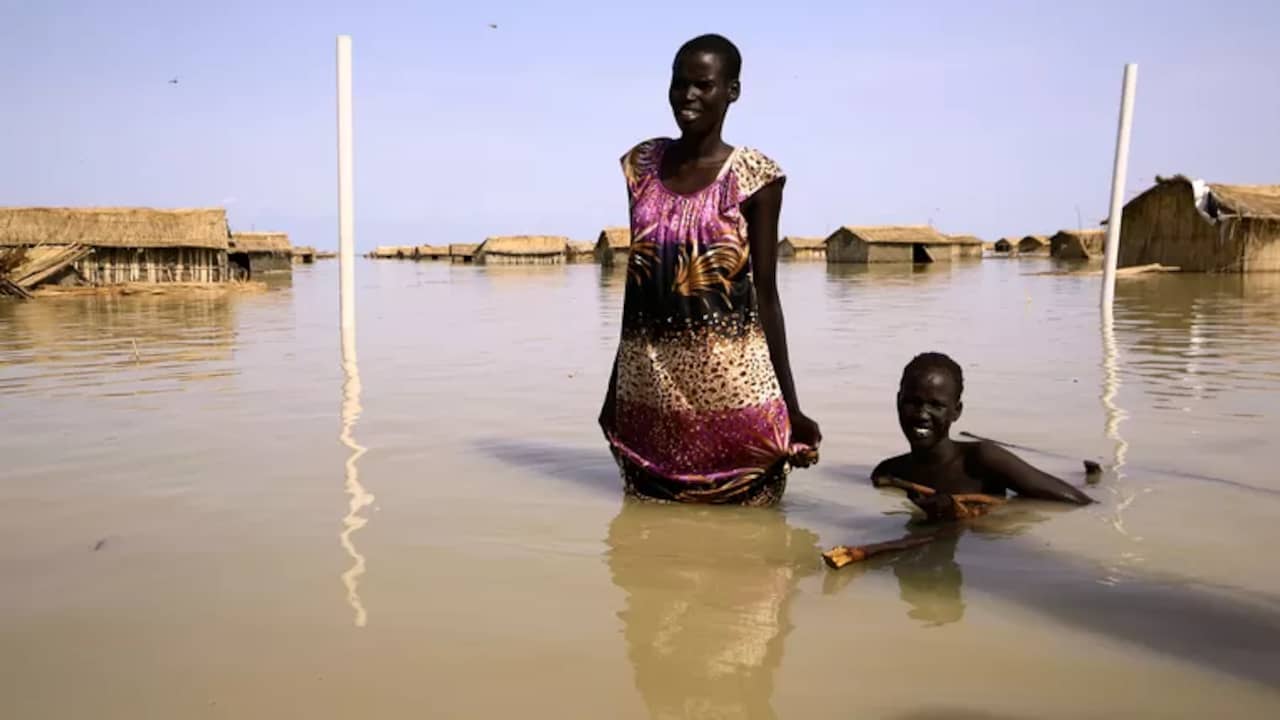 South Sudanese wade through the waters of the White Nile that has flooded their village.