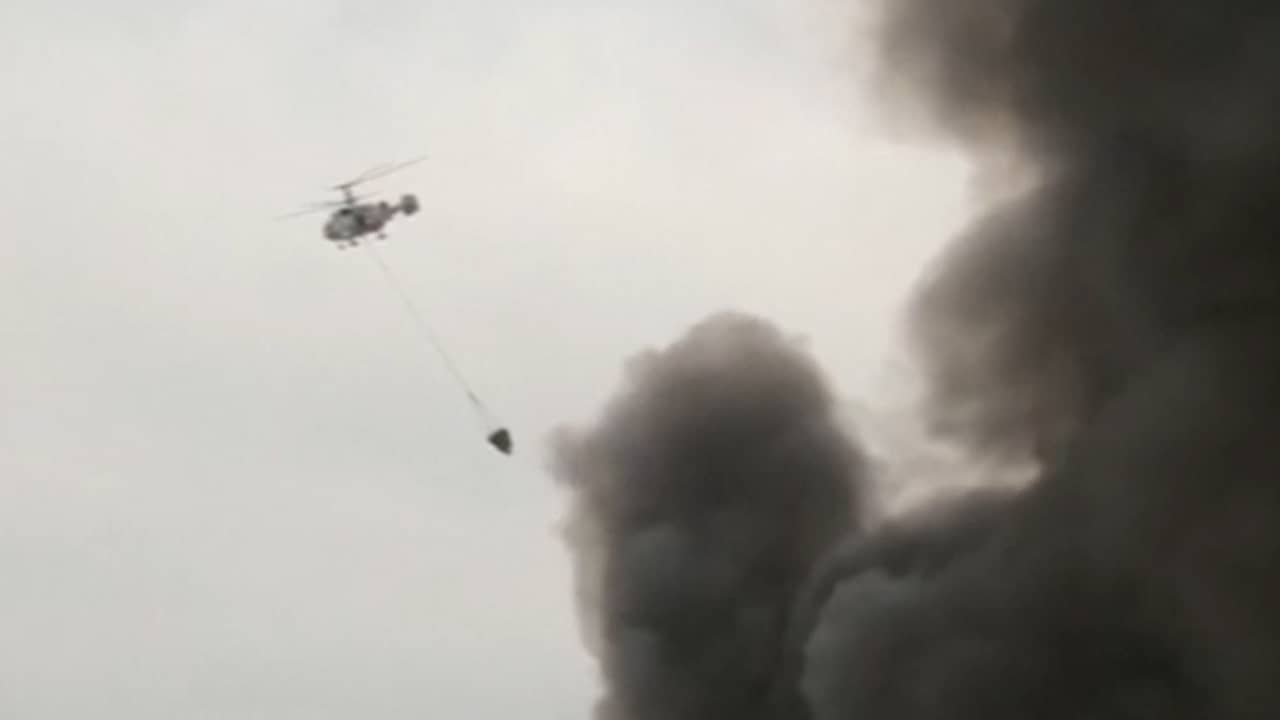 Blushelikopters lozen water boven grote brand in Moskou