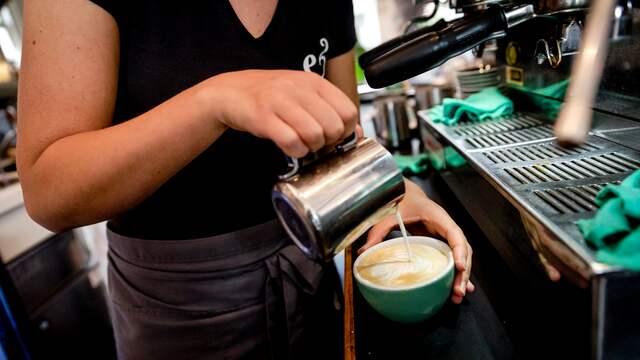 Een barista bereidt een cappuccino.