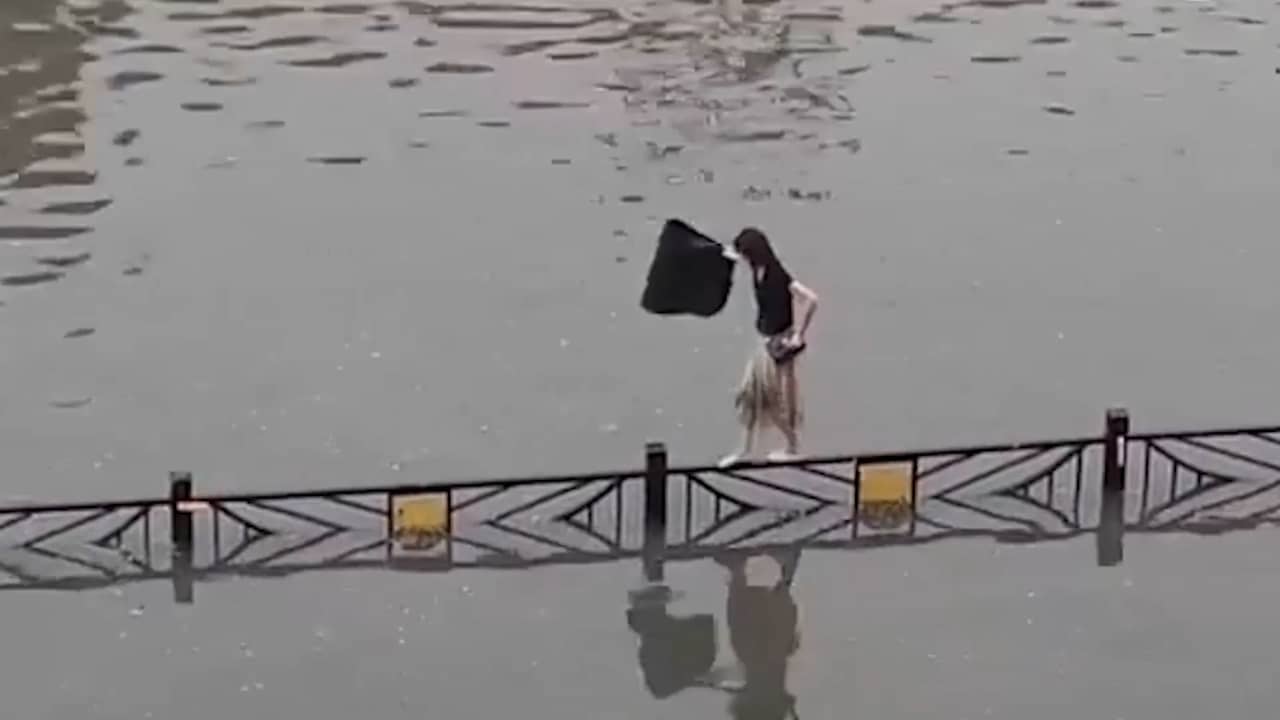 Beeld uit video: Vrouw balanceert op hek in overstroomd Chinees gebied