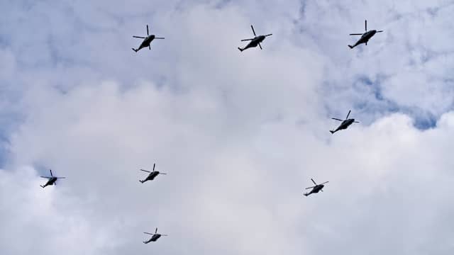 Acht gevechtshelikopters vliegen in formatie over Nederland