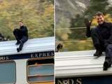 Tom Cruise zwaait naar fans tijdens stunt op dak van trein
