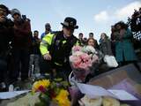 Een politieagent legt een bos bloemen bij de bloemenzee ter nagedachtenis aan de slachtoffers van de aanslag.