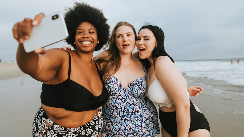 Vrouwen met smartphone maken selfie op het strand
