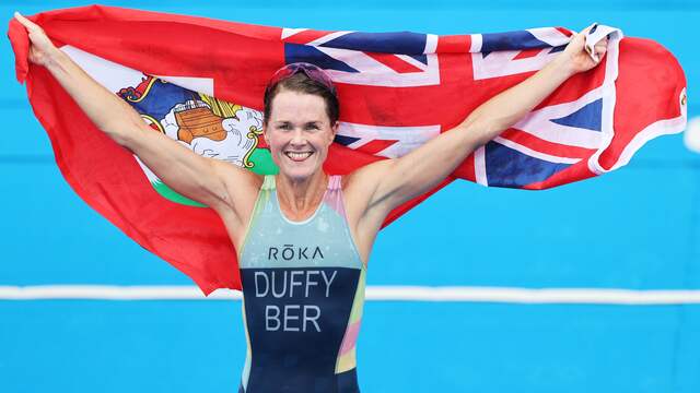 Flora Duffy juicht met de vlag van Bermuda na haar olympische titel op de triatlon.