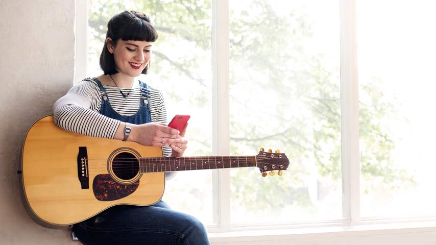 Vrouw met smartphone en gitaar