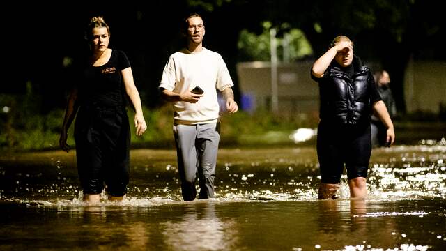 Bewoners lopen door een ondergelopen straat in Valkenburg aan de Geul. Door het alsmaar stijgende hoge water als gevolg van de de overstroming van de Geul zijn straten ondergelopen.