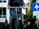 Een vrouw op de fiets trotseert de harde wind in Amsterdam. 