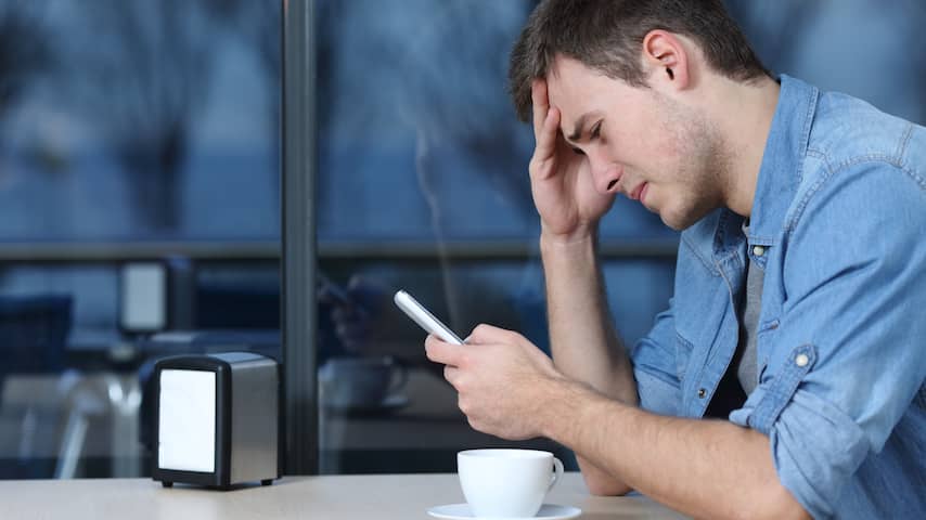 Verdrietige man in café met smartphone
