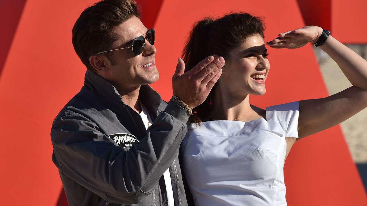 US actors and stars of the new movie Baywatch, Zac Efron (L) and Alexandra Daddario (R) wave to fans at a promotion for the movie on Bondi Beach in Sydney on May 17, 2017. The new Baywatch movie opens in cinemas on June 1, 2017. / AFP PHOTO / PETER PARKS
