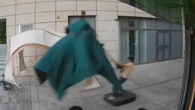 Man 'windsurft' met parasol tijdens stevige wind in China